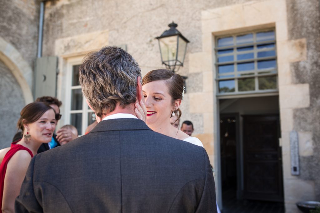 La mariée souriant à son mari dans la cour du château, entourée de ses invités