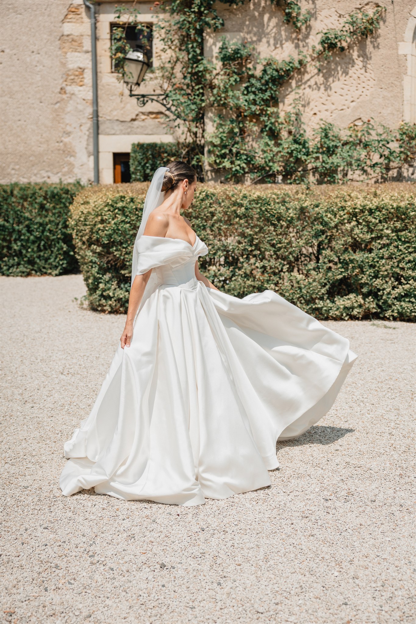 Bride in a silk ball gown crossing the courtyard of a château in Burgundy