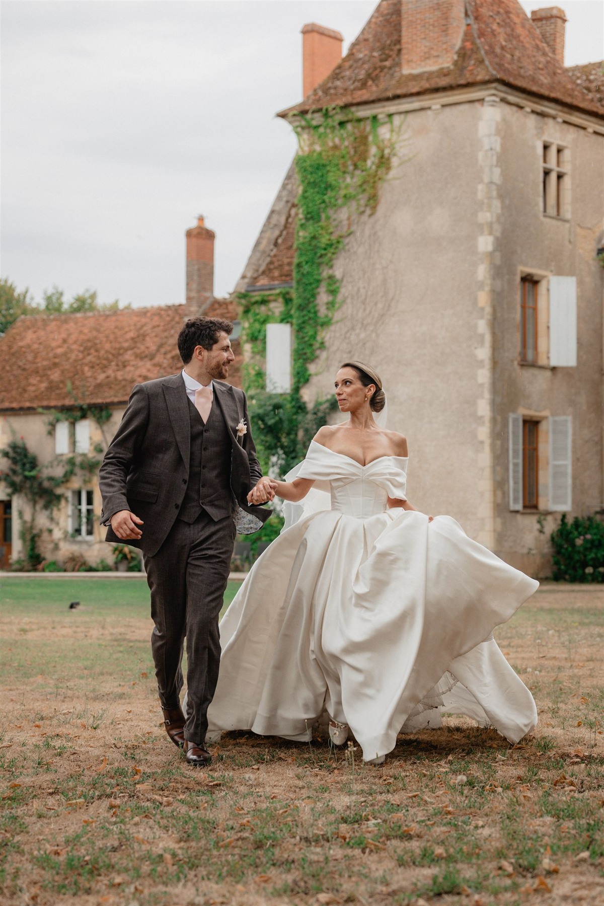 Les mariés marchant main dans la main devant le Château Le Sallay