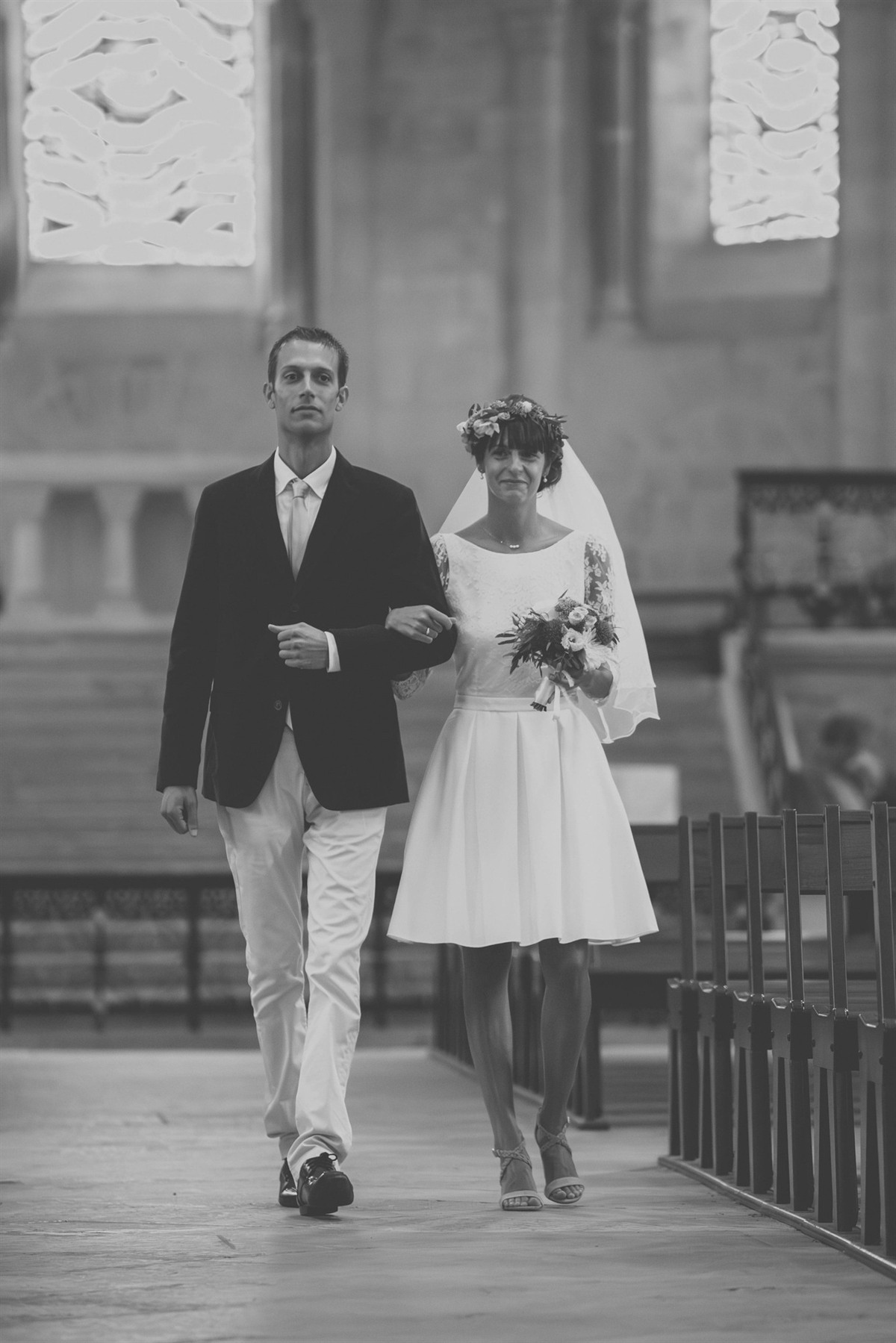 La mariée au bras de son père remontant l'allée de l'église, noir et blanc