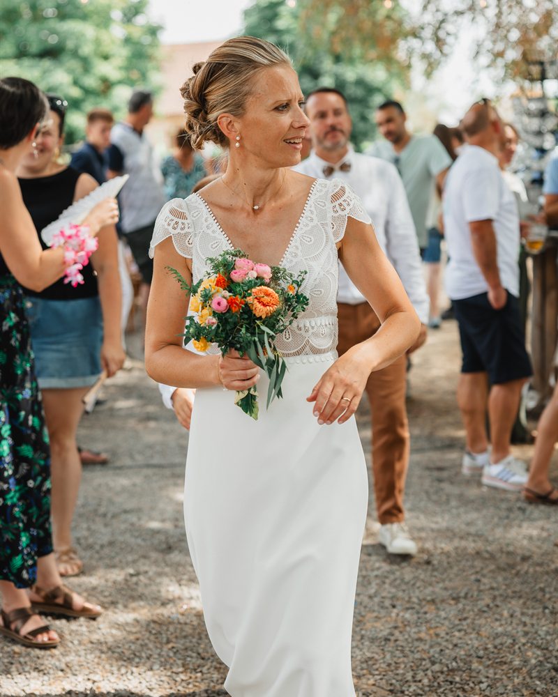 Mariée en robe à corsage de dentelle, bouquet coloré à la main, robe Mademoiselle a Dit Oui