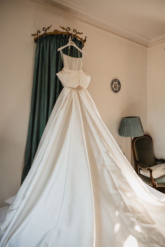 Robe de mariée suspendue dans une chambre de château