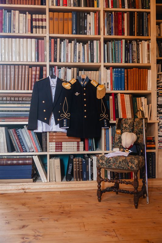 Uniformes de cérémonie suspendus devant les rayonnages d’une bibliothèque