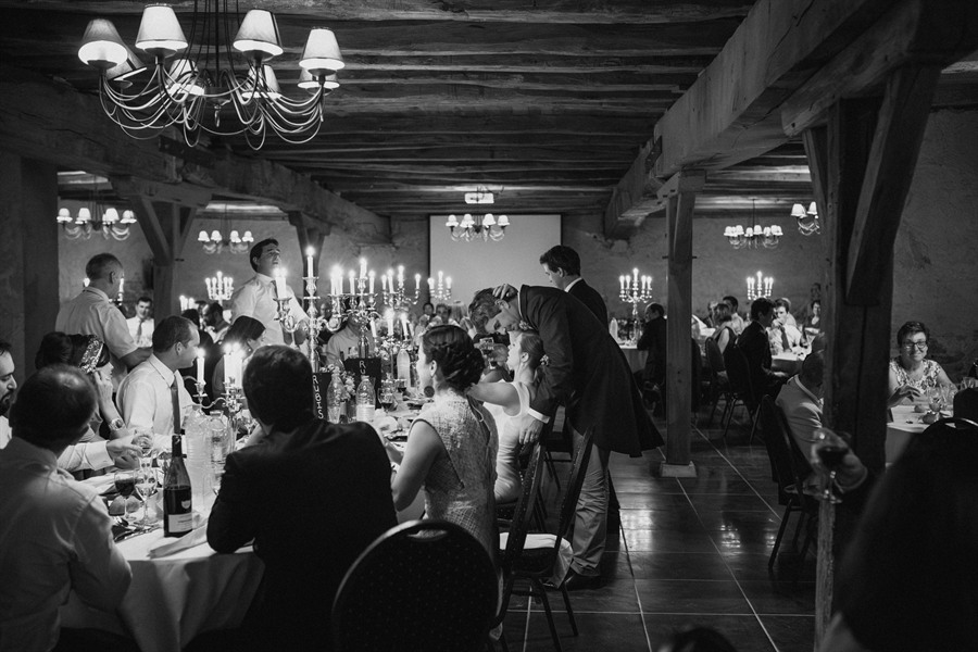 Le dîner de mariage dans une salle voûtée aux lustres, noir et blanc